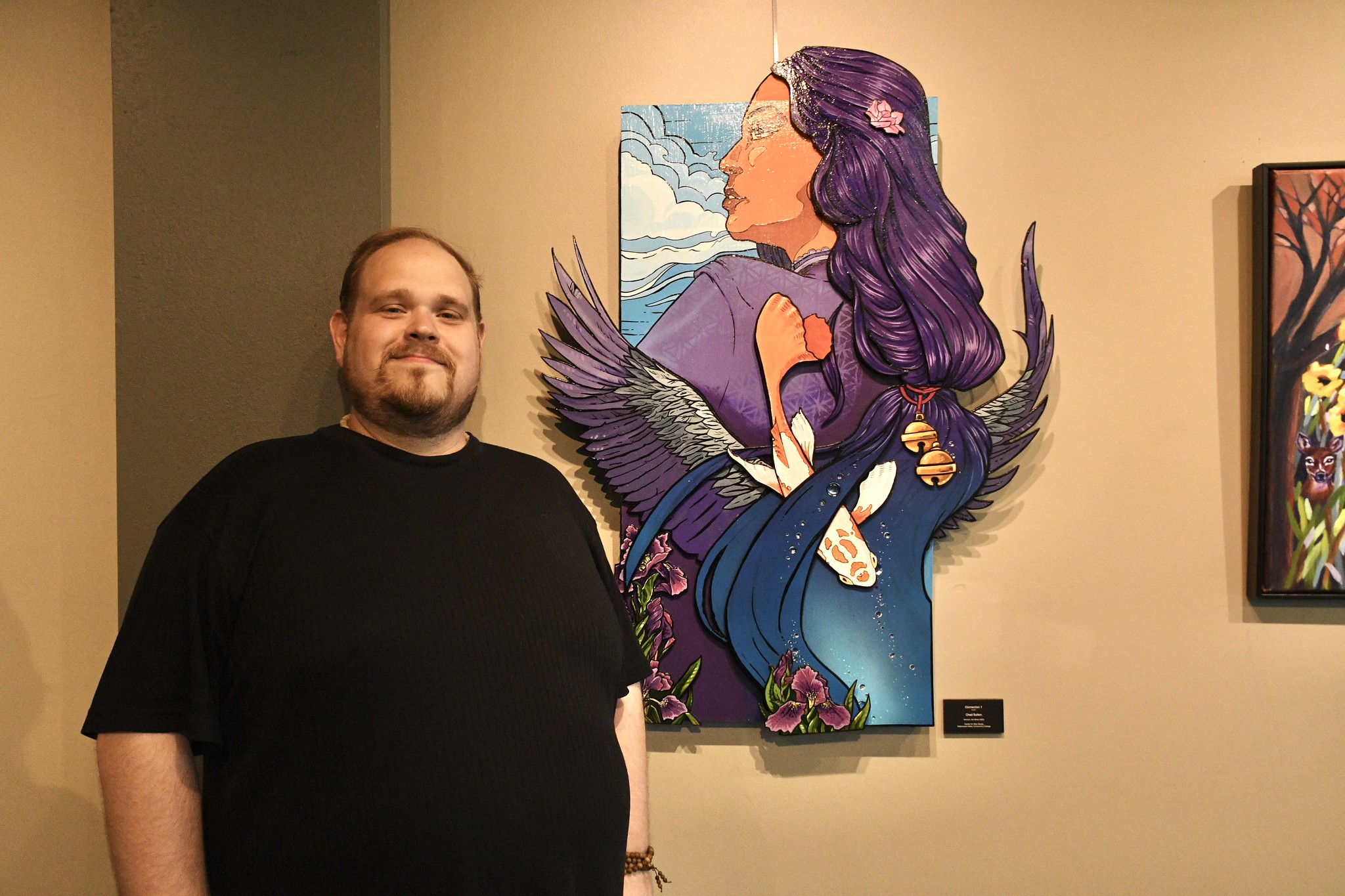 Chad Sutton poses next to his award-winning media sculpture after winning the 2025 Alumni Art Show.