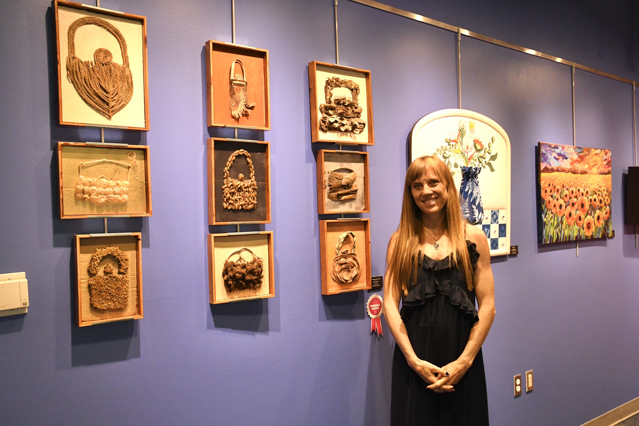Expressions through wood art: Alumna poses with her collection of wood art during the 2025 alumni art show.