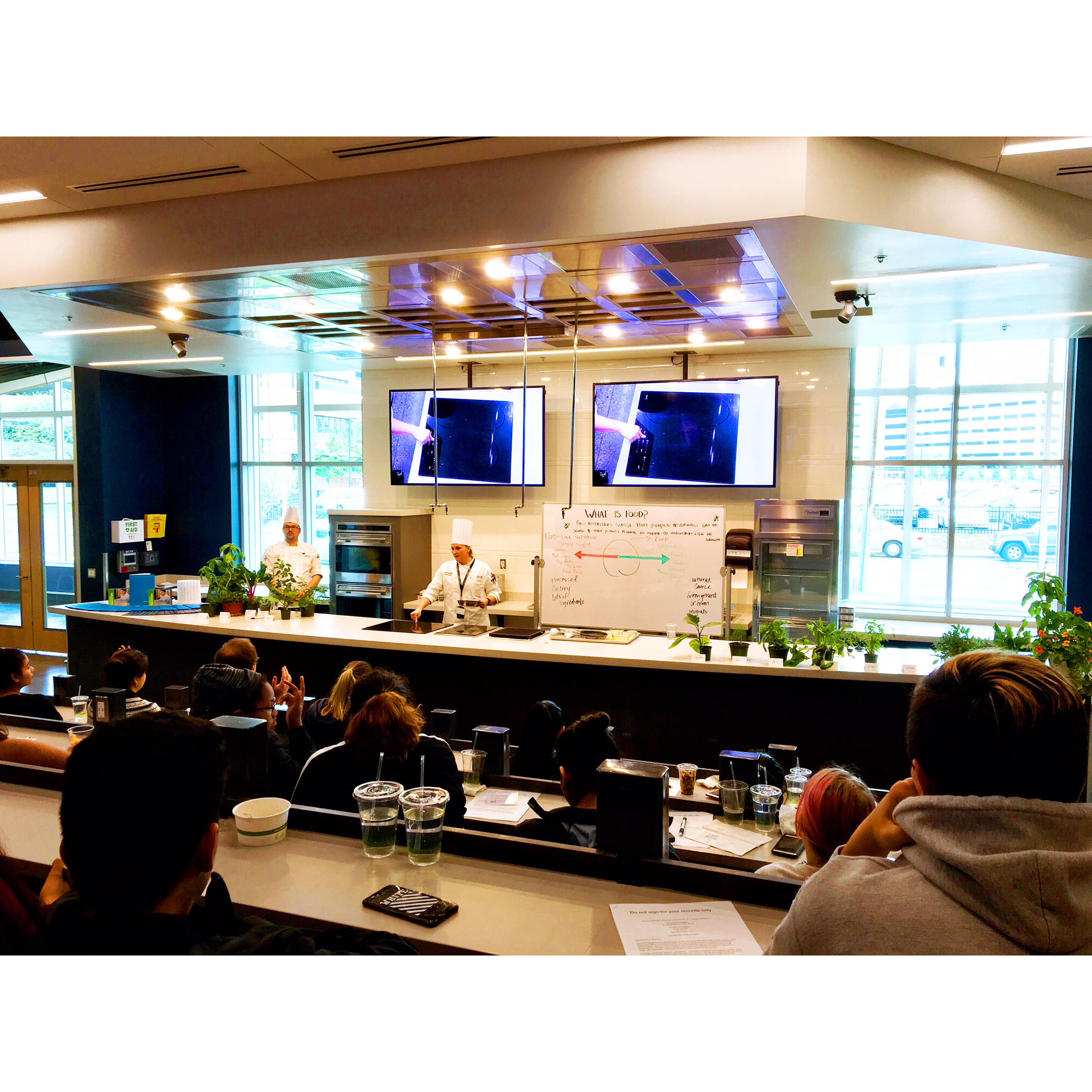 An instructor teaches students in a culinary classroom.
