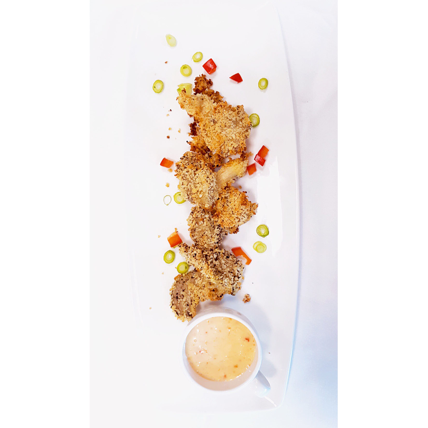 Fried mushrooms with dip on a tall plate.