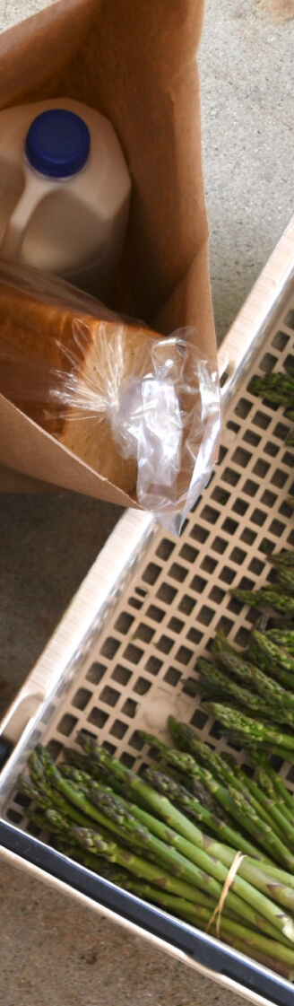 Food Share bag of milk, bread, and a crate of bundled asparagus.