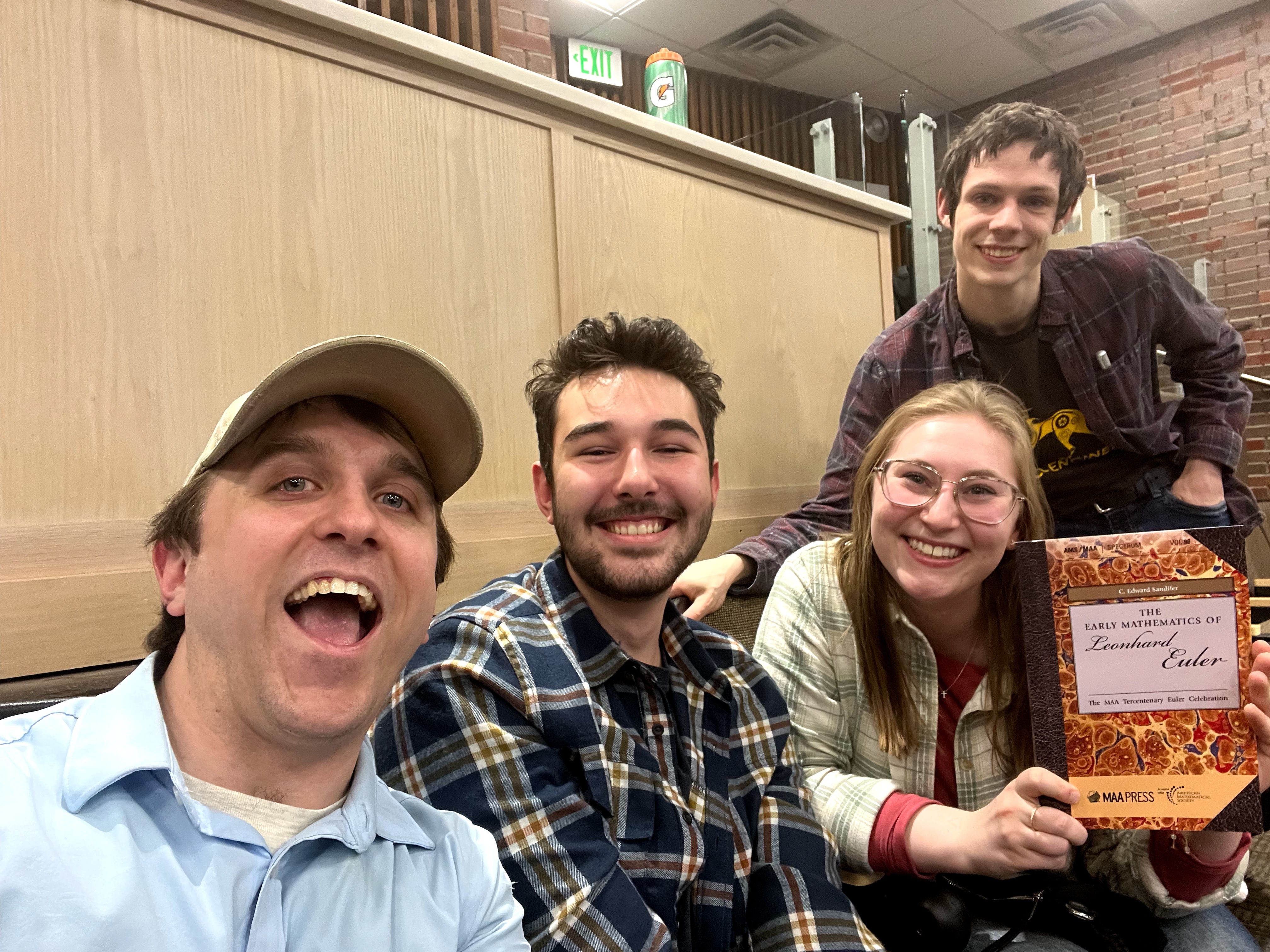 Four contestants smiling, one posing with an award.